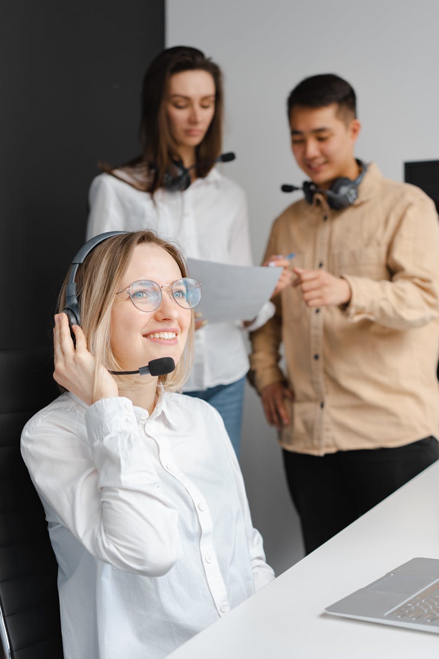 woman in a white shirt smiling while holding her headset